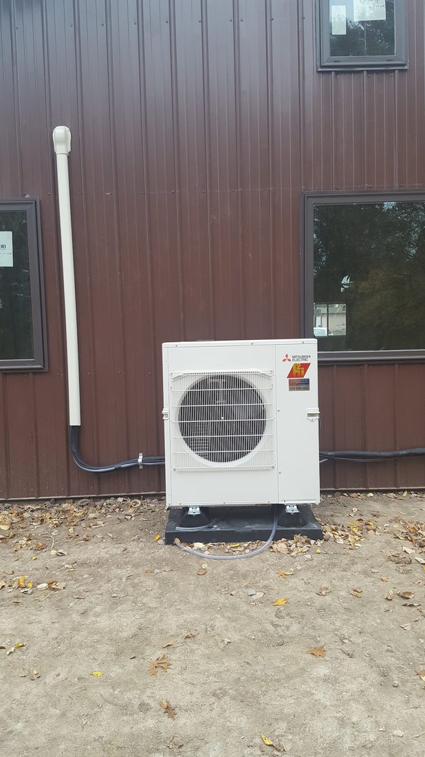 Mitsubishi mini-split outdoor unit installed against a metal-sided building